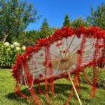 Ombrelle mariage rouge translucide avec détails floraux, idéale pour photos artistiques et cérémonie élégante au style unique.