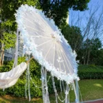 Ombrelle mariage blanche avec touches ivoire, design raffiné à fleurs et perles, idéale pour mariage chic en extérieur et ambiance poétique.