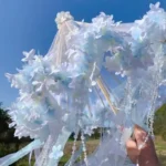 Ombrelle mariage bleu ciel translucide, ornée de fleurs délicates et perles, idéale pour photos élégantes et mariage romantique en plein air.